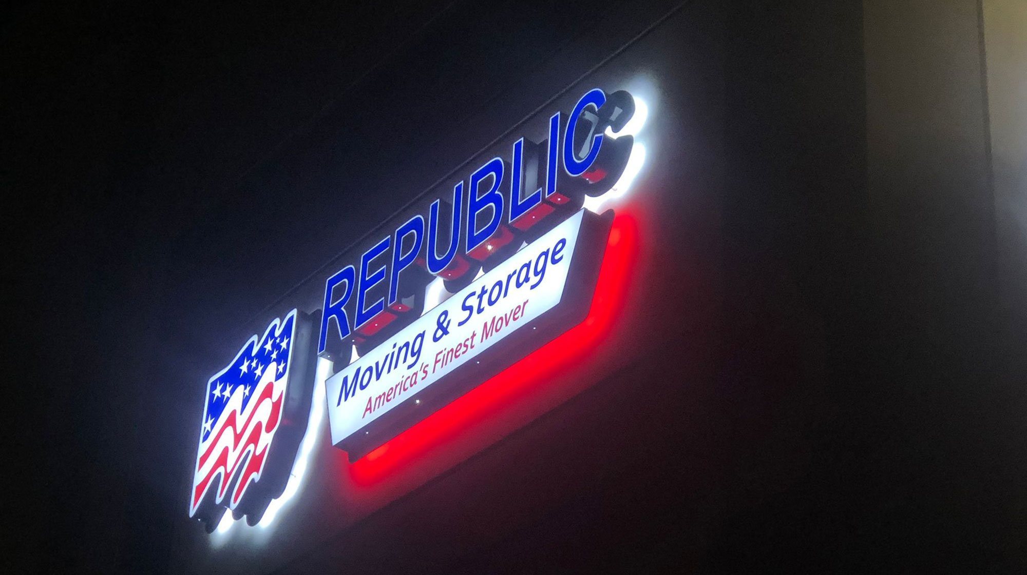 Illuminated sign for Republic Moving & Storage with American-themed design at night.