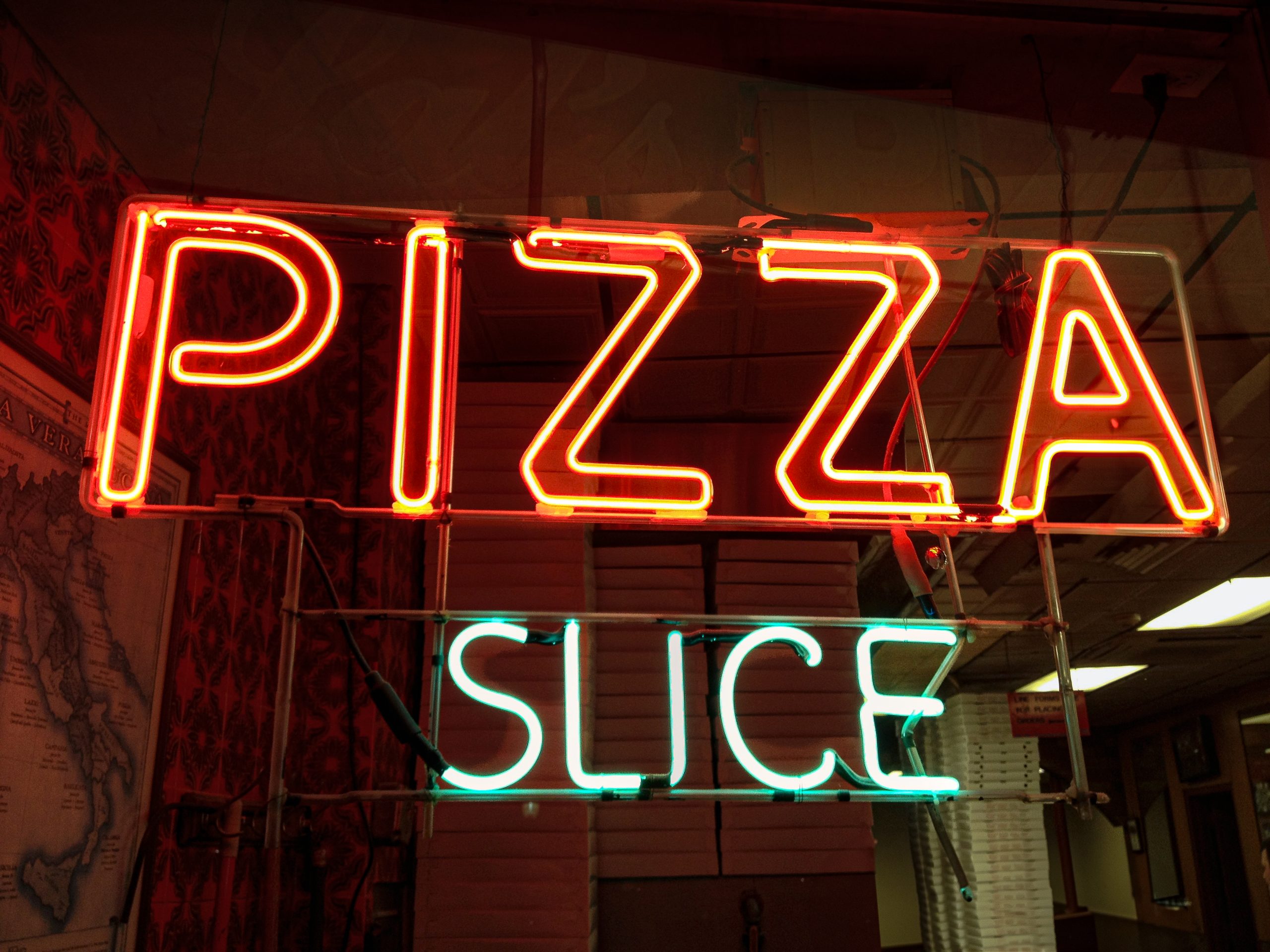 lluminated Signs Neon sign with "PIZZA SLICE" glowing in red and blue.